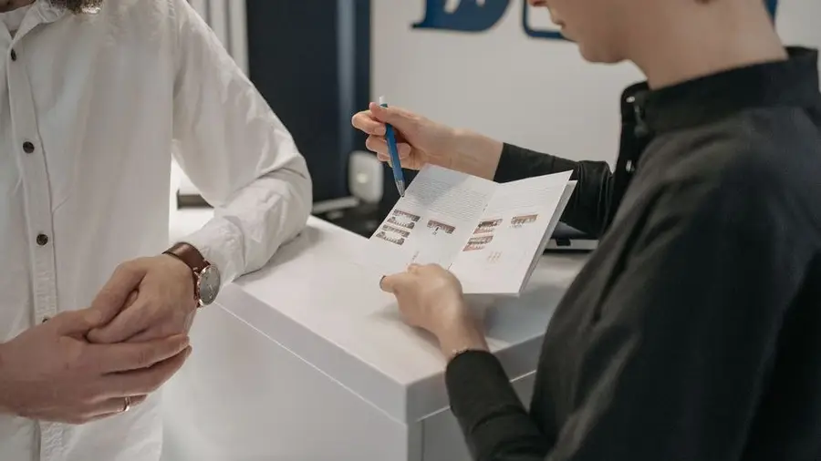 Receptionist speaking with a visitor at a bright clinic front desk