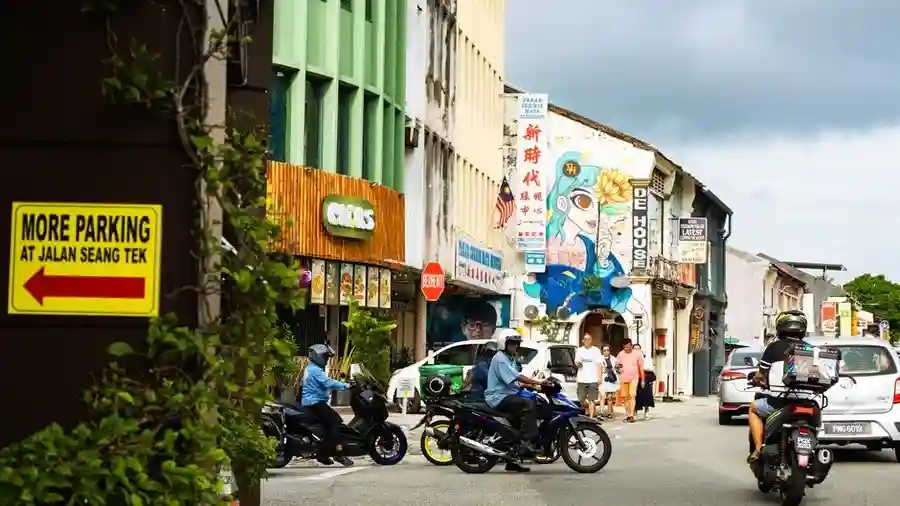 Busy George Town street with motorbikes and shophouse signs