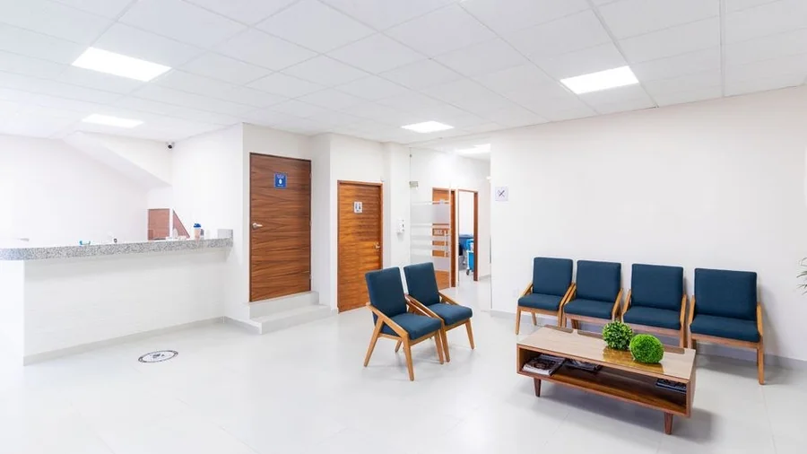 Bright clinic waiting area with reception counter and empty seating