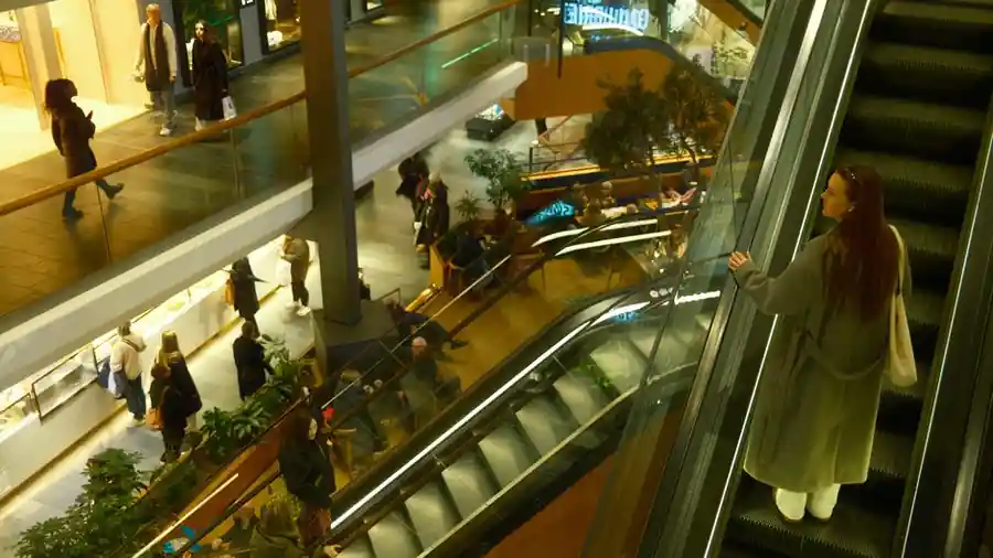 Interior of a multi-level shopping centre with escalators and shoppers on the upper floors