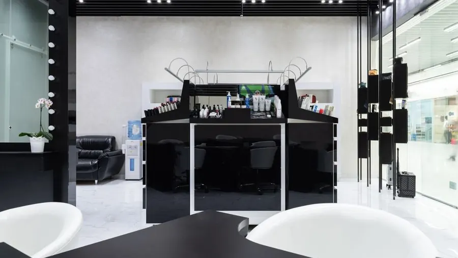 Modern salon interior with dark treatment stations, white basins and pendant lighting