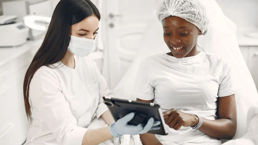 Dermatologist consulting with a patient at a clinic desk with a laptop
