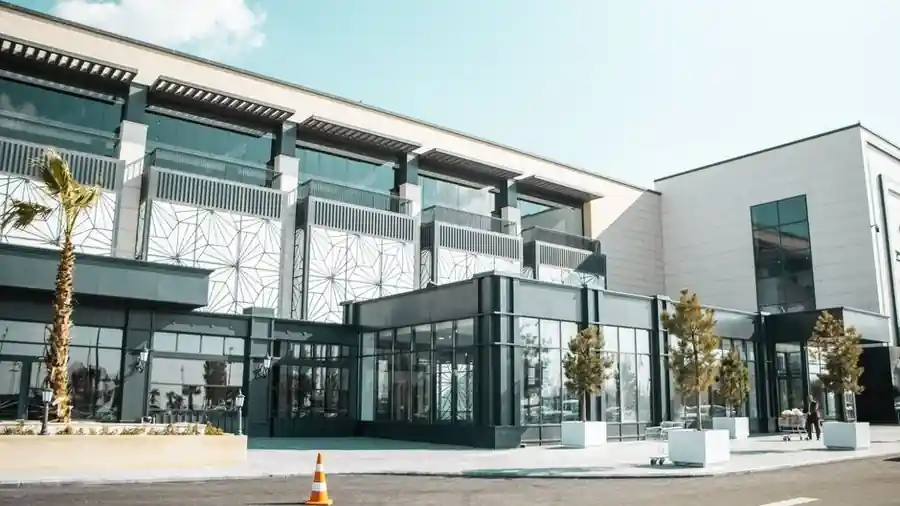 Modern shopping mall exterior with glass storefront and palm trees