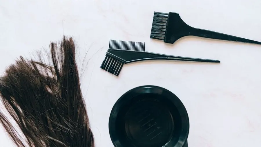Hair dye brush, bowl and gloves laid out on a white surface