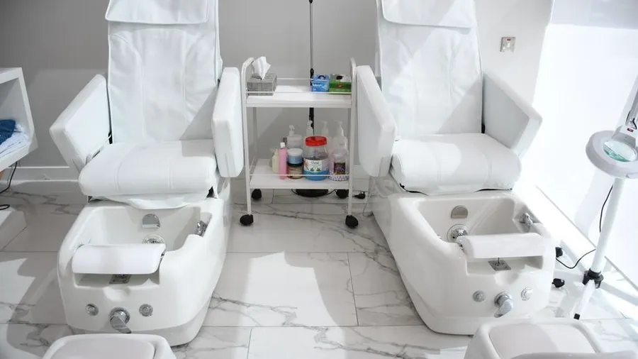 Pedicure chairs in a bright nail salon with marble flooring