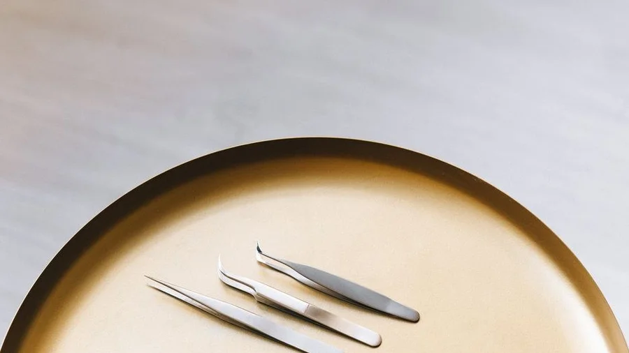 Metal tweezers resting on a beige tray