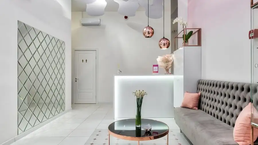 Bright beauty salon reception with a pink sofa and mirrored wall