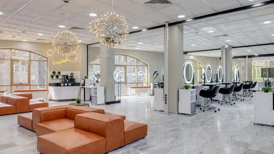 Spacious hair salon with round mirrors and an orange lounge sofa