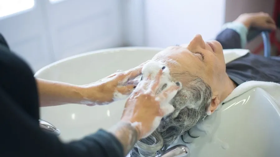 Stylist washing a client's hair at a salon basin
