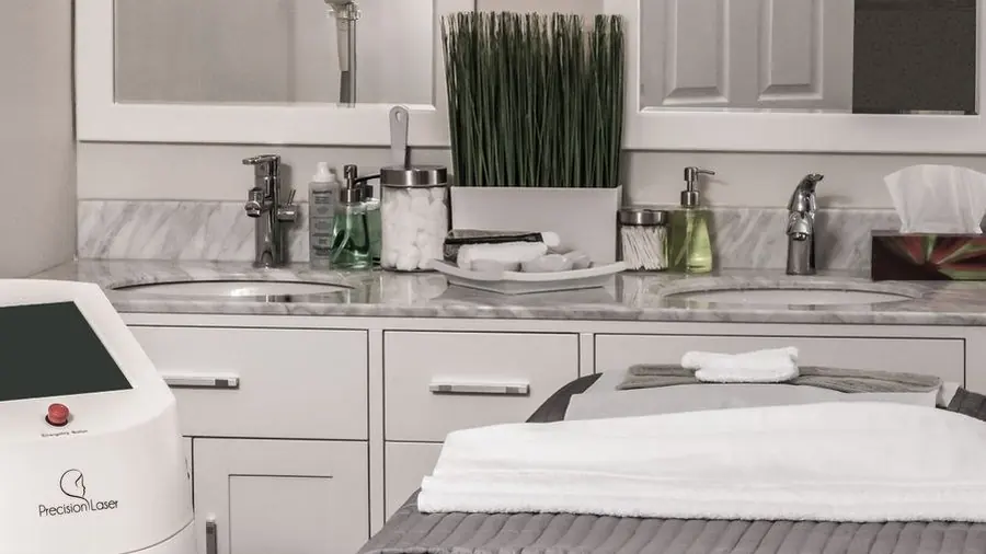 Clean modern treatment room with a padded bed and equipment trolley