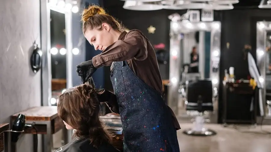 Stylist blow-drying a client's hair at a salon station