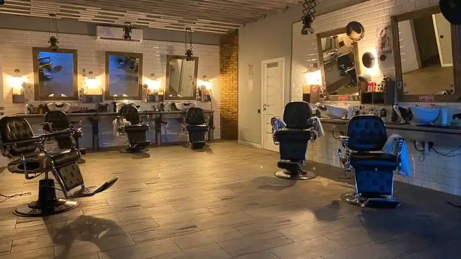 Empty hair salon interior with styling chairs, mirrors and warm wall lighting