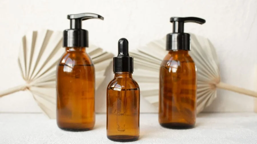 Amber glass skincare bottles with dropper and pump tops on a shelf