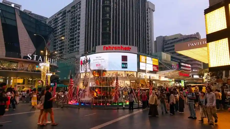 Crowded Bukit Bintang junction at dusk with shopping malls and lit signs