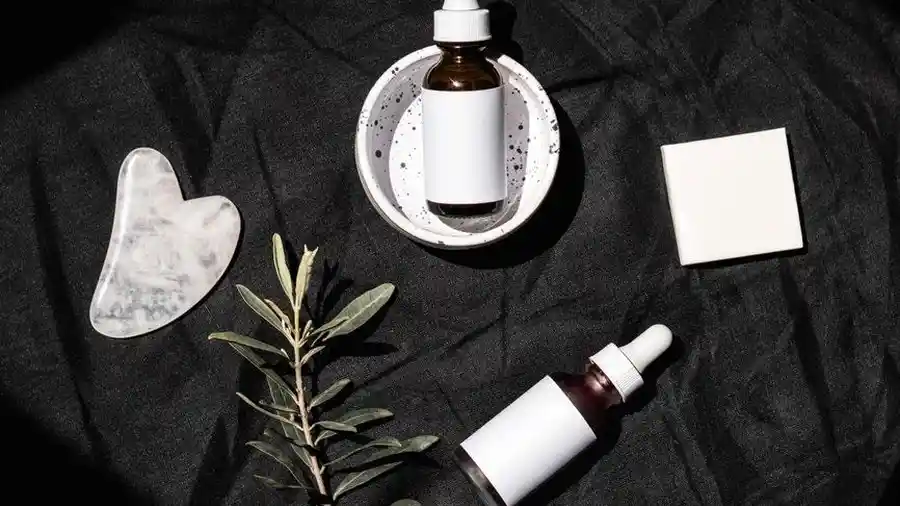 Dropper bottles and a facial tool on a dark surface