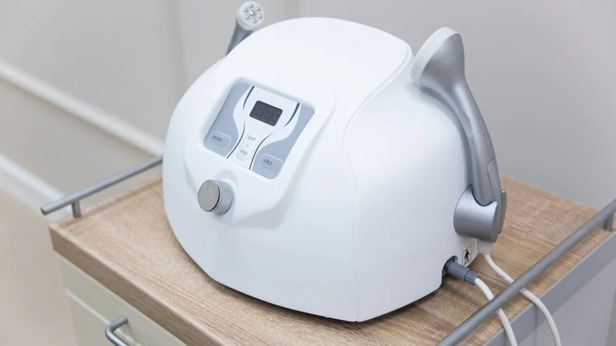 Aesthetic laser device with handpiece resting on a clinic trolley