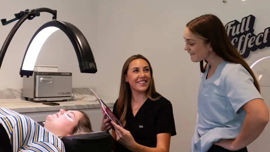 Bright clinic treatment area with a light panel and staff talking to a client