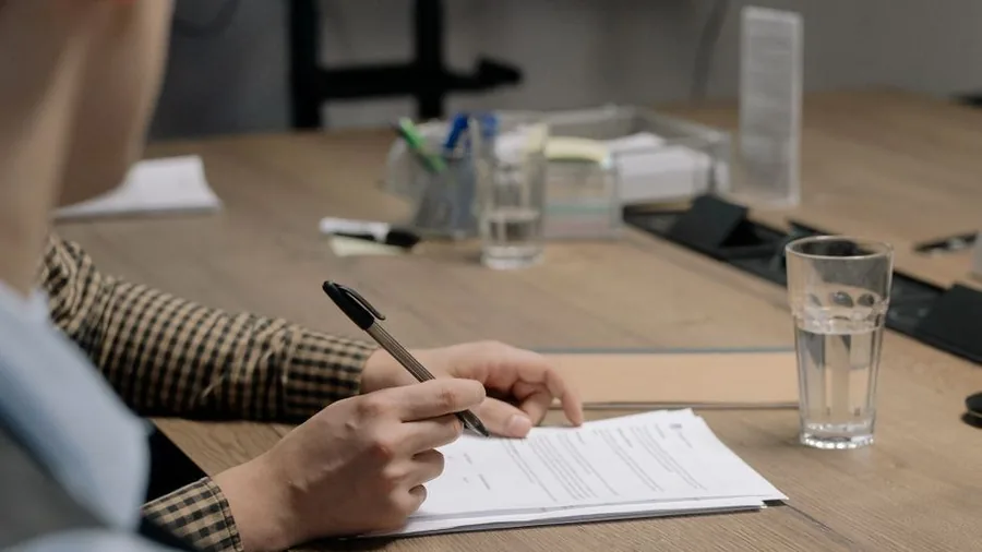 Hands filling in a clinic consent form at a consultation desk