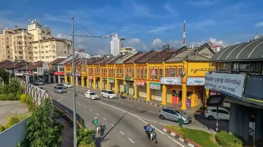 Row of yellow shophouse storefronts along a Malaysian main road