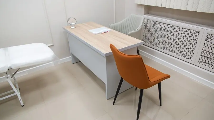 Clinic consultation room with a desk, chair and treatment bed