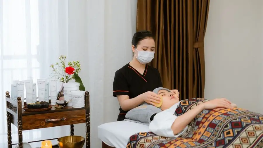 Beautician performing a masked facial skincare treatment on a client