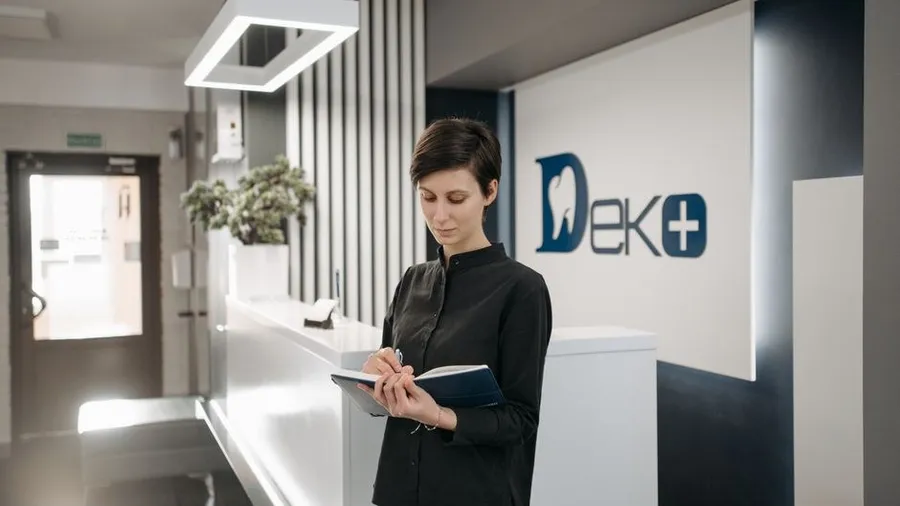 Modern clinic reception desk with a staff member assisting a visitor