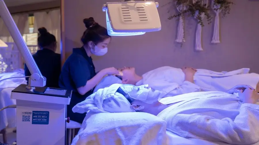 Patient receiving a light-based skin treatment while lying on a clinic bed