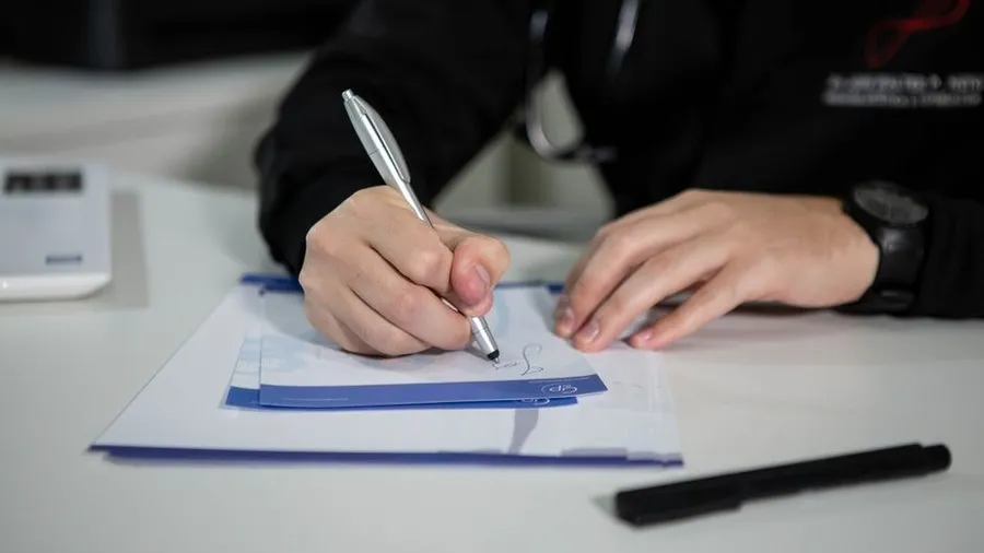 Person writing notes on a form at a desk