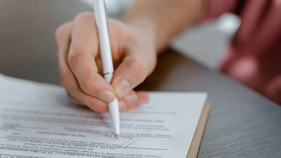 Person signing a consent form on a clipboard