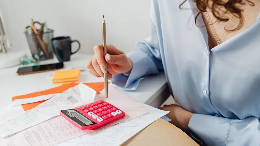 Desk with a calculator, printed paperwork and a pen during cost planning