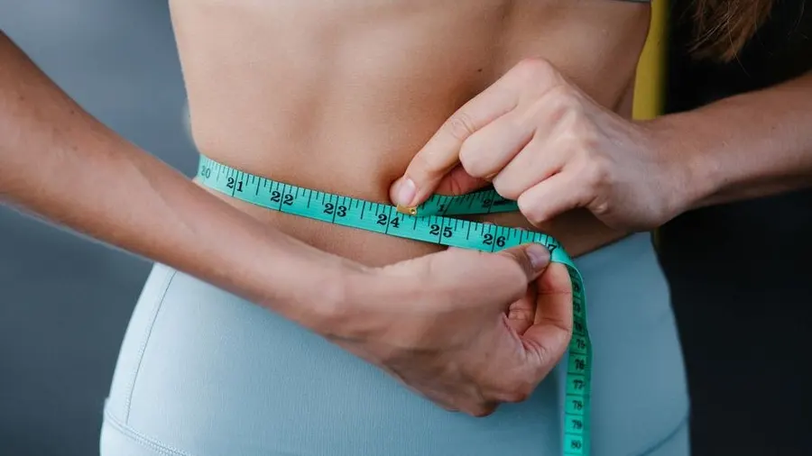 Close-up of a measuring tape around a waist during a body assessment