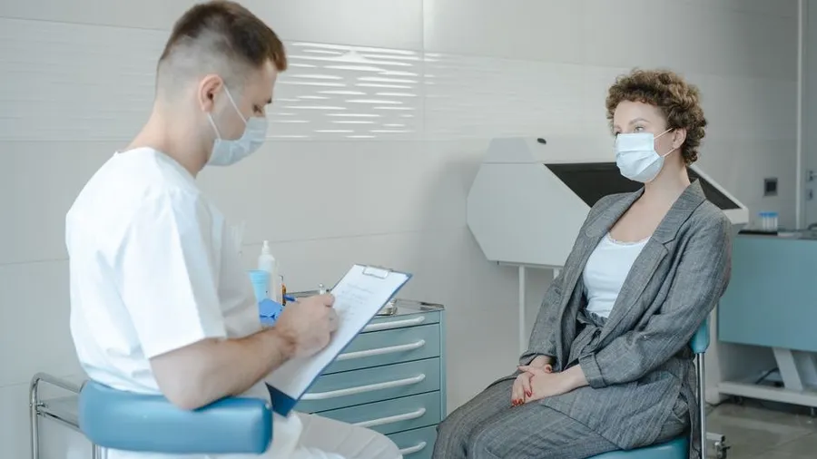 Doctor holding a clipboard while consulting with a patient