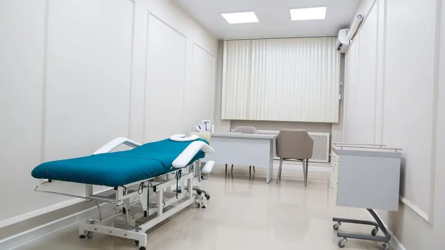 Modern clinic treatment room with examination bed and desk