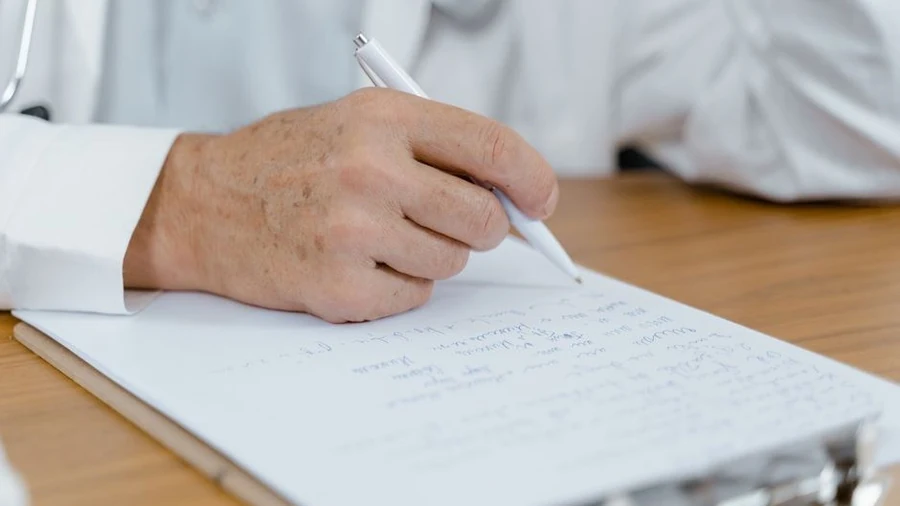 Practitioner writing consultation notes on a clipboard