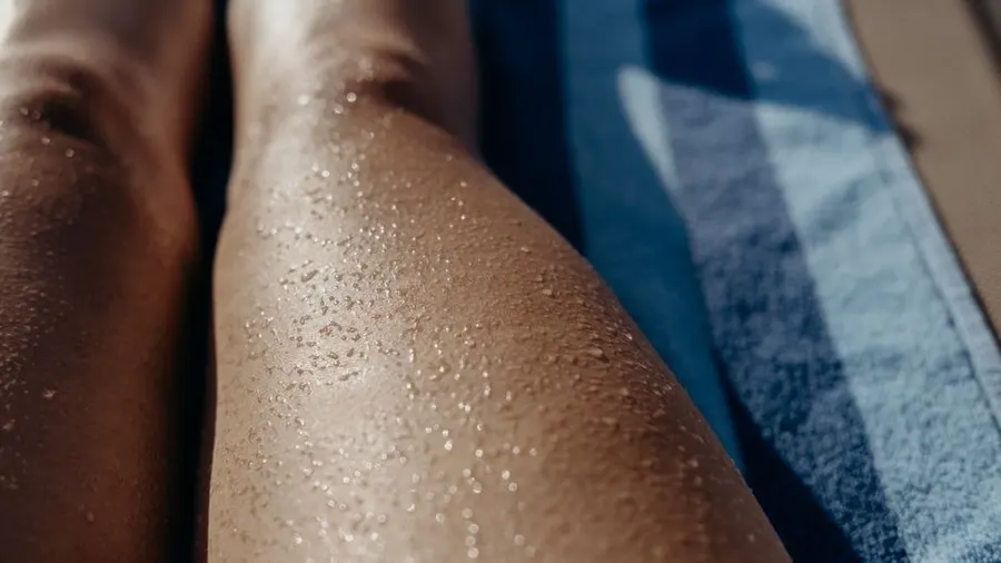 Close-up of legs resting on a blue towel