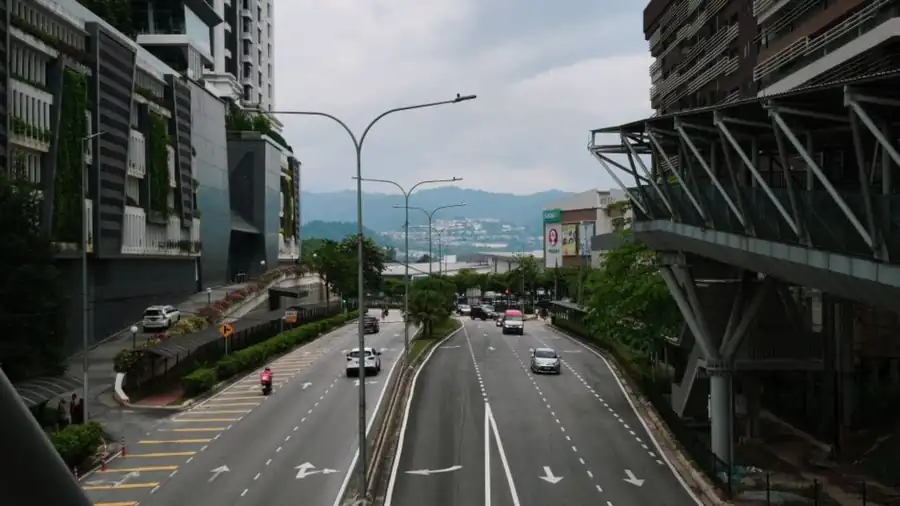 Wide Klang Valley road lined with greenery and low commercial buildings