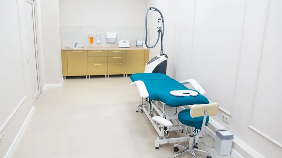 Bright treatment room in a medical clinic with a laser device beside the couch