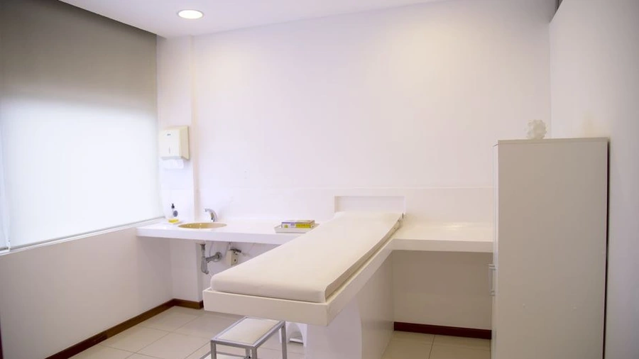 Minimalist white treatment room with an examination bed and cabinet